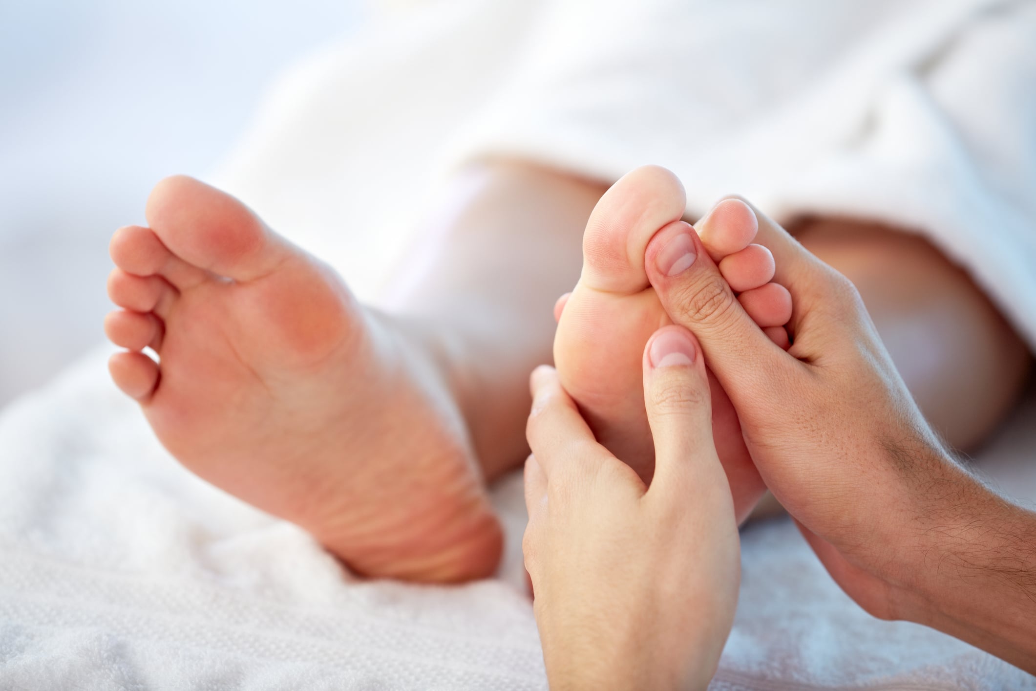 mains effectuant de la réflexologie sur des pieds